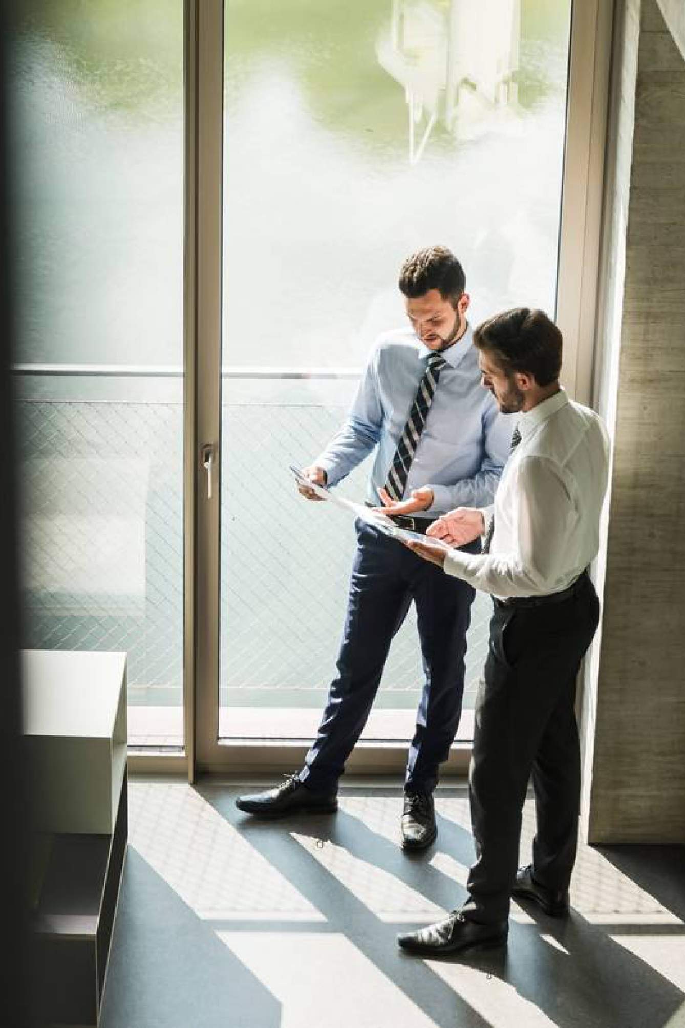 Two commercial real estate analyst talking near window